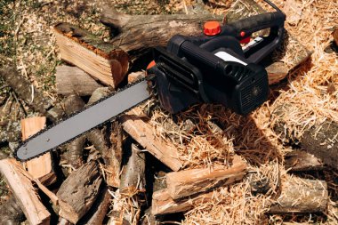 Elektrikli testere yakın çekim. Bir aletle testere. Yakacak odunun arka planında elektrikli testere