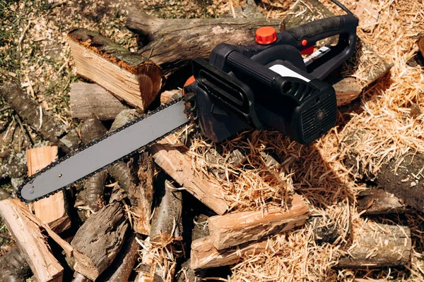 Elektrikli testere yakın çekim. Bir aletle testere. Yakacak odunun arka planında elektrikli testere