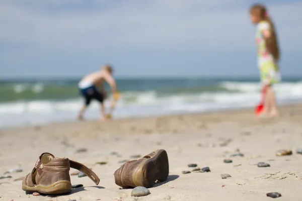 Kids sandals and children at the beach — Stock Photo, Image