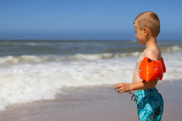 Menino com asas de água laranja na praia — Fotografia de Stock