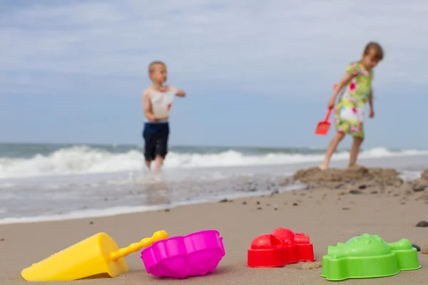 Two kids and colourful plastic toys at beach — Stock Photo, Image