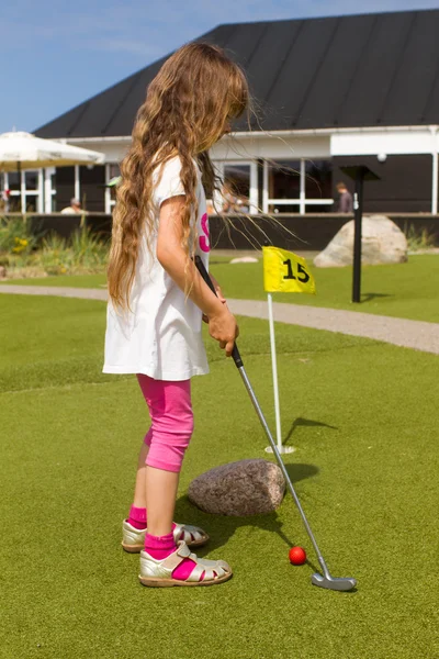Девочка с длинными волосами играет в мини-гольф — стоковое фото