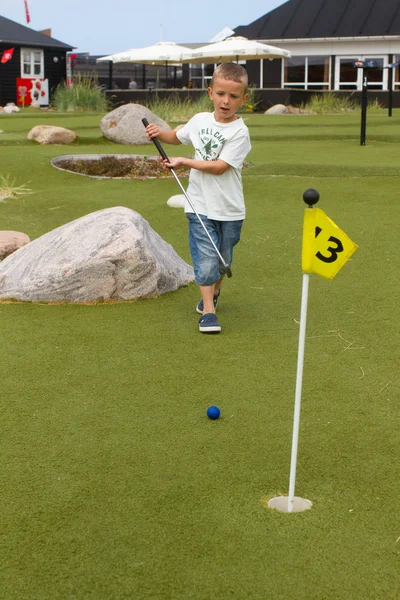 Мальчик играет в мини-гольф летом — стоковое фото