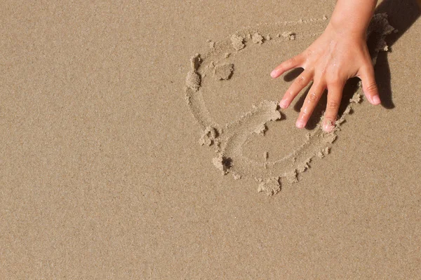 Kid hand tekenen van een hart in het zand — Stockfoto