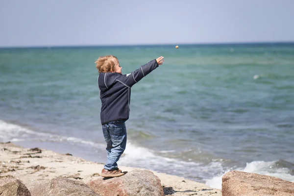 Garçon jetant des pierres à la plage — Photo