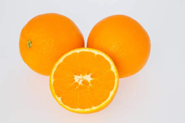 A Cut Orange in front of Two Oranges — Stock Photo, Image