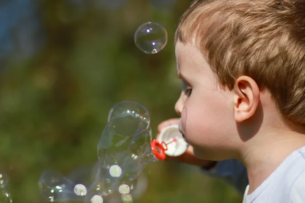 Хлопчик дме бульбашки — стокове фото