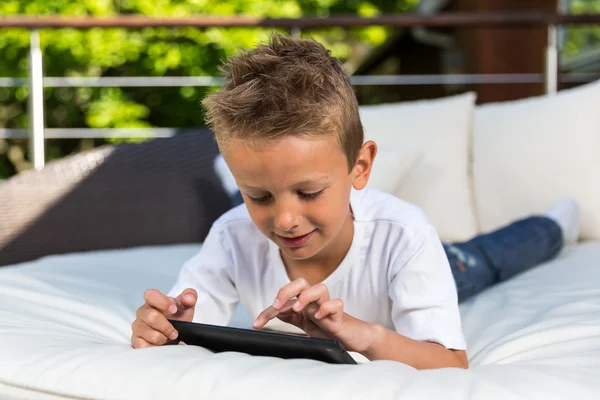 Chlapec vleže s jeho tablet — Stock fotografie