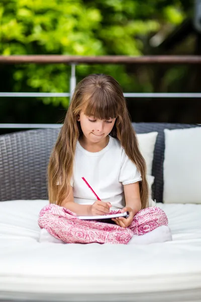 Girl writing at notepad — Stock Photo, Image