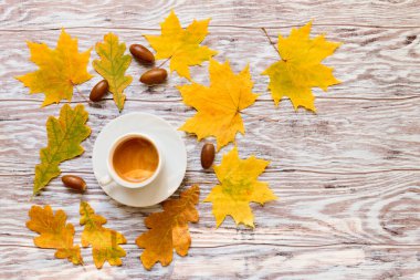 Sarı akçaağaç, meşe yaprağı ve meşe palamudu ile bir fincan kahve, sonbahar havası, düz uzanma, ahşap zemin üzerinde metin için alan