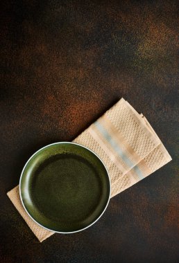 Mutfak havlusunda grunge tarzı boş yeşil tabak, üst manzara, koyu arkaplan