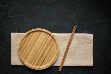 Boş bambu tabağı, yemek çubukları ve koyu arkaplan üzerine peçete, Japon yemek şablonu, fotokopi alanı ile üst görünüm, düz yatış