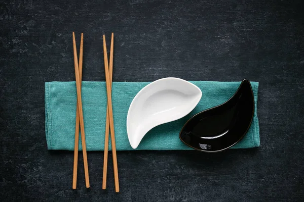 黑白相间的陶瓷碗和筷子躺在亚麻布餐巾上 深色背景 顶视图 图库图片