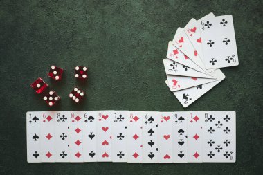 Zarlı yeşil desenli arkaplan ve üzerinde oyun kartları var.