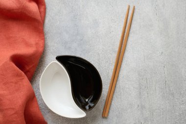 2 ceramic bowls, bamboo chopsticks, and a linen napkin on a concrete table with space for text