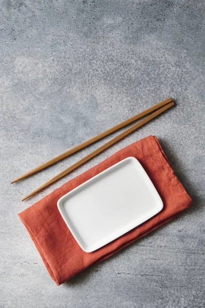Çubuklu keten peçeteye boş beyaz tabak, kopyalama alanı olan gri arkaplan