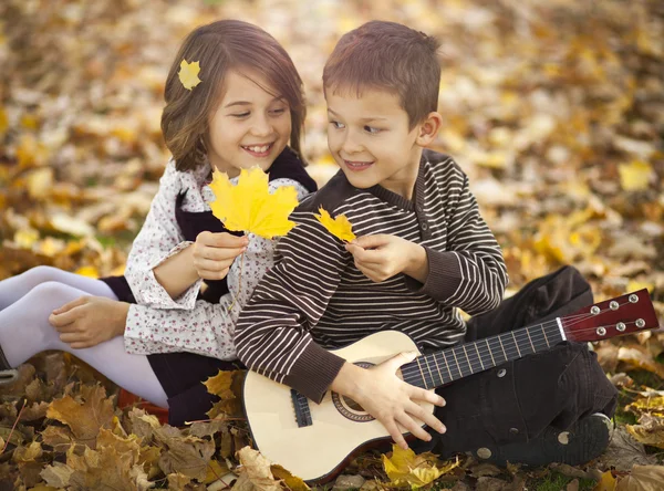 Happy kids in park with autumn leaves — Stock Photo, Image