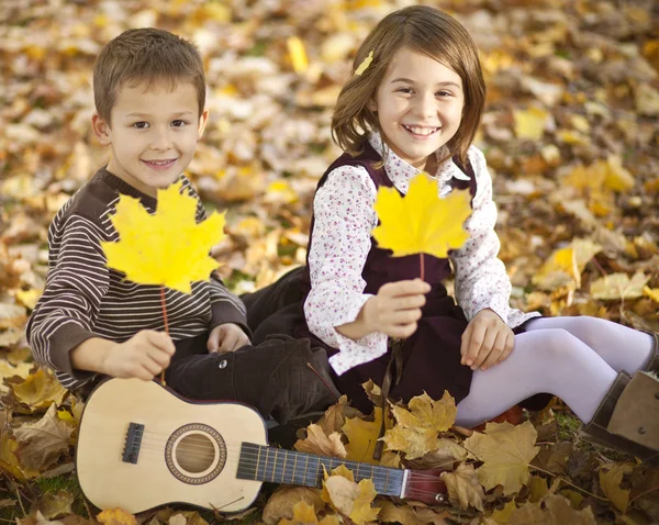 Happy kids in park with autumn leaves — Stock Photo, Image