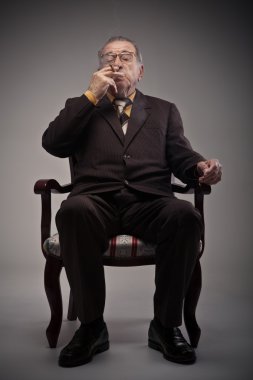 ihtiyar bir sandalyede oturan ve Sigara