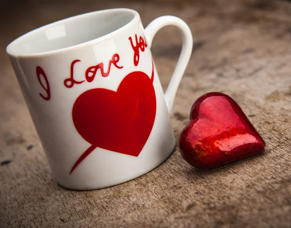 Red heart and mug on wooden background — Stock Photo, Image