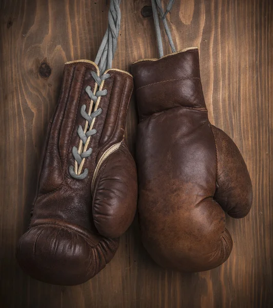 Guantes de boxeo viejos marrones con un encaje sobre una pared de madera vieja — Foto de Stock