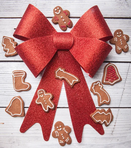 Arc rouge sur fond en bois et biscuits de Noël — Photo