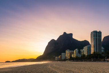 Rio de Janeiro 'daki Boş Sao Conrado Plajı' nda gün batımında lüks apartmanlar ve Pedra da Gavea Manzarası