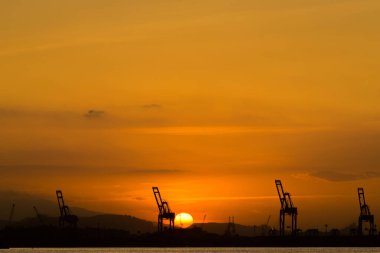 Industrial Cranes in the Horizon With Sun Setting Behind