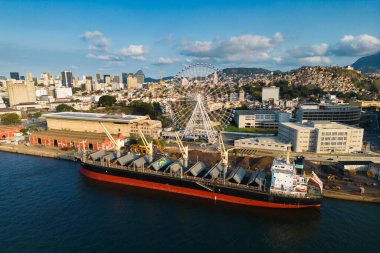 Rio de Janeiro, Brazil - August 3, 2022: Aerial view of Yup Star (Rio Star) ferris wheel and large industrial cargo ship.