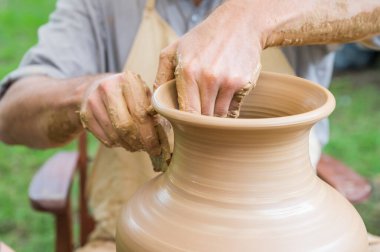 Çömlekçi çarkında kil vazo yapan bir adamın elleri.