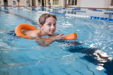 Çocuk kapalı havuzda yüzmeyi öğreniyor.