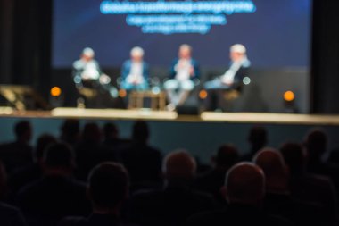 Erkekler konferansı düzenliyor ve seyirciler ön planda - kasıtlı olarak bulanık