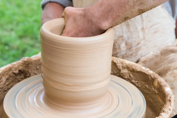 Hands of a man making a clay vase on a potter\'s wheel