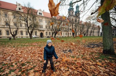 Tarihi bir manastırın önündeki parkta yaprakları atan bir çocuk.
