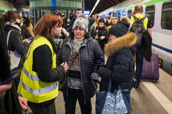 WROCLAW, POLAND - 11 Mart 2022: Wrocaw 'daki tren istasyonunda Ukraynalı savaş mültecilerine yardım. Fotoğraflı Polonyalı gönüllüler mültecilere yardım ediyor.