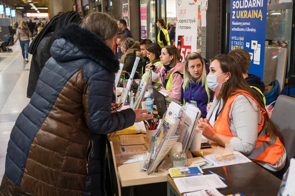 WROCLAW, POLAND - 11 Mart 2022: Wrocaw 'daki tren istasyonunda Ukraynalı savaş mültecilerine yardım. Fotoğraflı Polonyalı gönüllüler mültecilere kabul noktasında yardım ediyor.