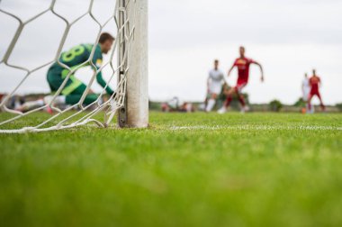 Net ve kale futbol kalesinde ve kaleci ve arka planda oyuncular.