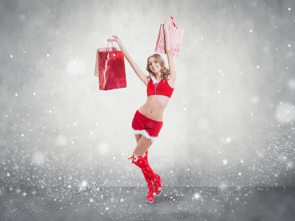 美丽性感的女孩穿着圣诞老人的衣服雪片状混凝土墙背景概念 — — 圣诞快乐圣诞新年 — 图库照片