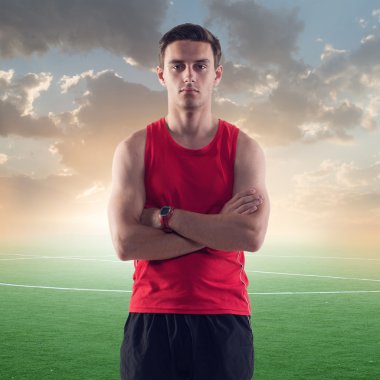 atletik erkek, arka planı yeşil futbol futbol sahası ile mavi gökyüzü günbatımı üzerinde sporcu