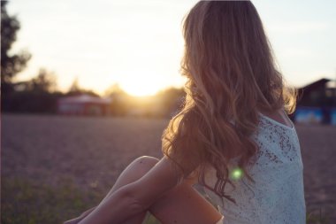 güneşli güzel genç romantik kadın veya sahilde günbatımı keyfi doğa yaz akşam açık havada izlerken beyaz elbiseli kız portresi. yumuşak ışık. güneş ışığı. tonda sıcak renkler.