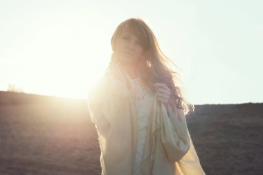 Sahilde günbatımı ışık, altında açık havada dikey yürüyen genç bir kadın. yumuşak ışık ve güneş.