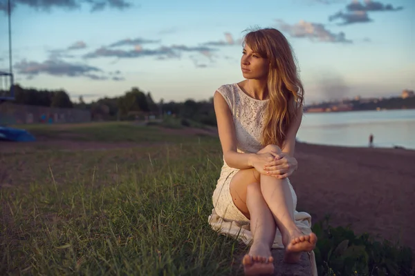 Joven belleza sonriente chica relajante mujer sentada cerca de río o lago en la naturaleza al aire libre retrato. Colores cálidos soleados suaves. Puesta de sol rayos de sol. Foto estilo tonificado filtros de Instagram —  Fotos de Stock