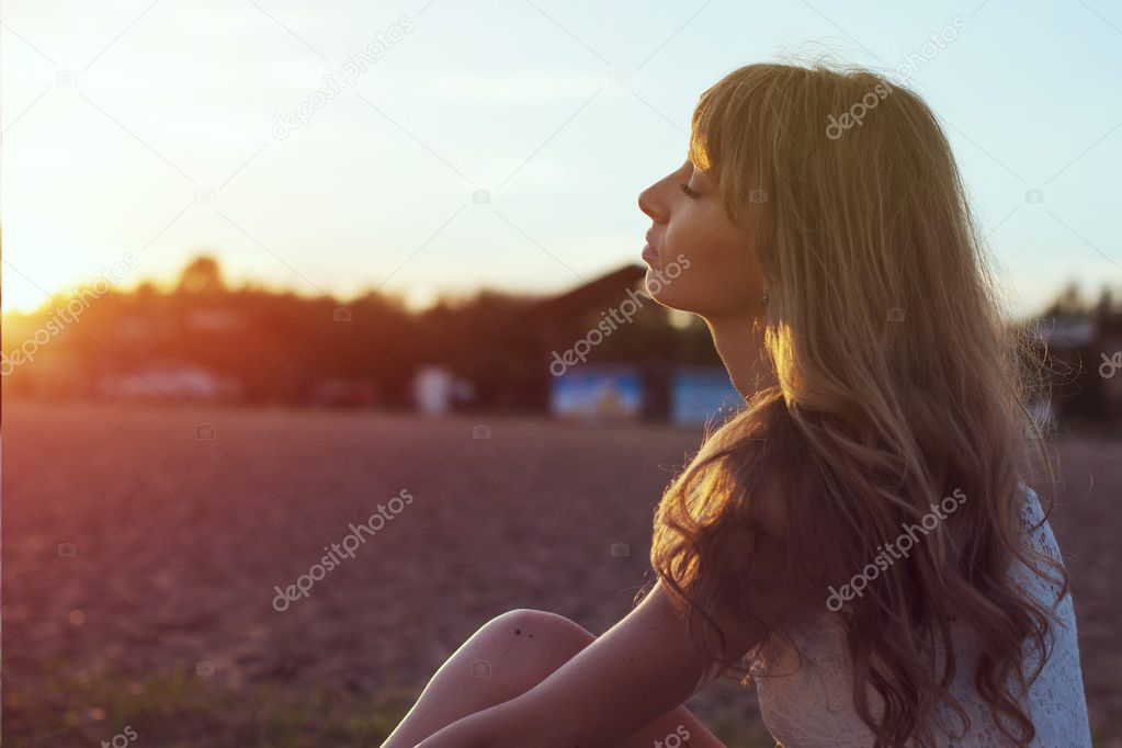 Young woman walking on beach under sunset light, outdoors portrait. Soft light and Sunshine.