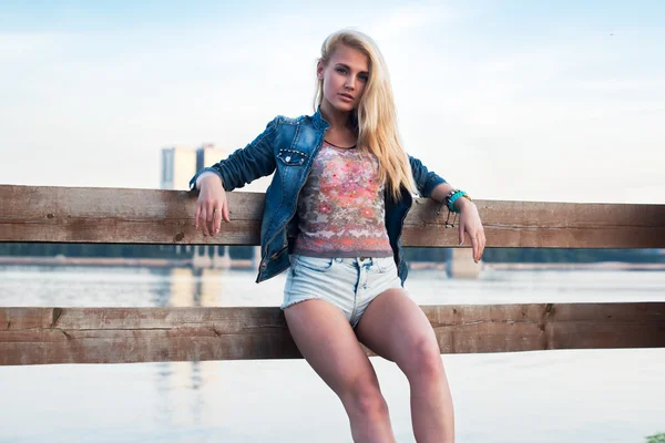 Retrato ao ar livre de moda romântica jovem com pernas longas e cabelo em roupas casuais de verão em pé no cais perto do rio. Estilo de vida urbano. Foto tonificada cores quentes — Fotografia de Stock