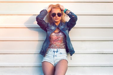 Genç şık açık yaz portre portre çekici kadın veya kız sokak Kot ceket ve beyaz duvara yakın duran güneş gözlüğü güneşli günde yarattığı moda