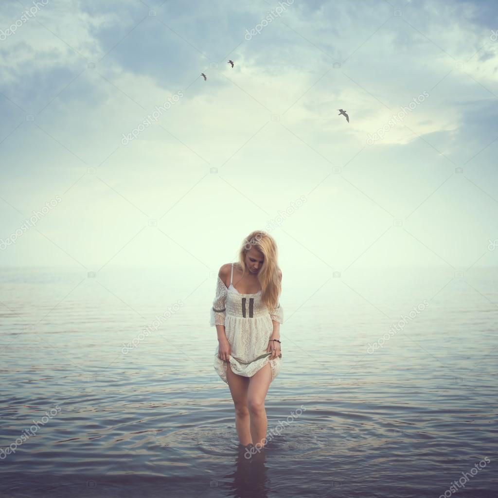 Beautiful girl in the water. Beach, sunrise, cold morning. concept loneliness love sadness romance