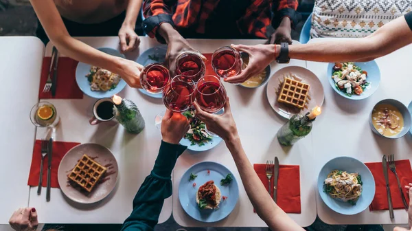 Freunde sitzen an einem Tisch und trinken Weingläser — Stockfoto