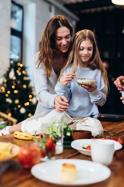 Mor och dotter i köket. Flicka sitter på bordet, vinterhelg, semester humör — Stockfoto