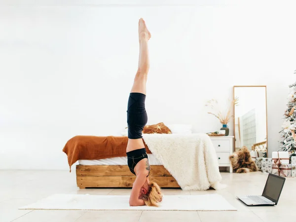 Jonge fitte vrouw doet headstand oefening thuis. — Stockfoto