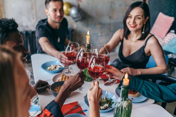 Amici seduti a tavola a bere vino bicchieri di clinking. — Foto Stock